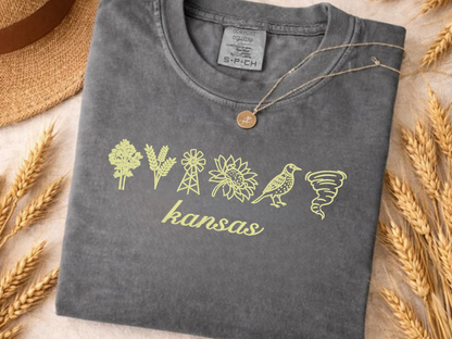 Close-up of Kansas symbols embroidered in yellow on a charcoal Comfort Colors shirt