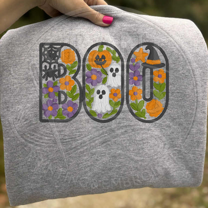 Close-up of floral BOO embroidery with ghosts, pumpkins, flowers, spiderweb, and witch hat on sport grey youth sweatshirt