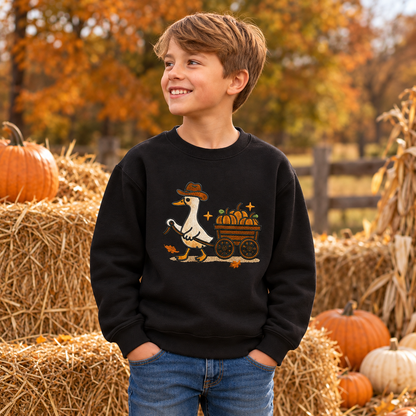 Boy wearing Black youth sweatshirt with raised embroidered pumpkin wagon goose beside pumpkins