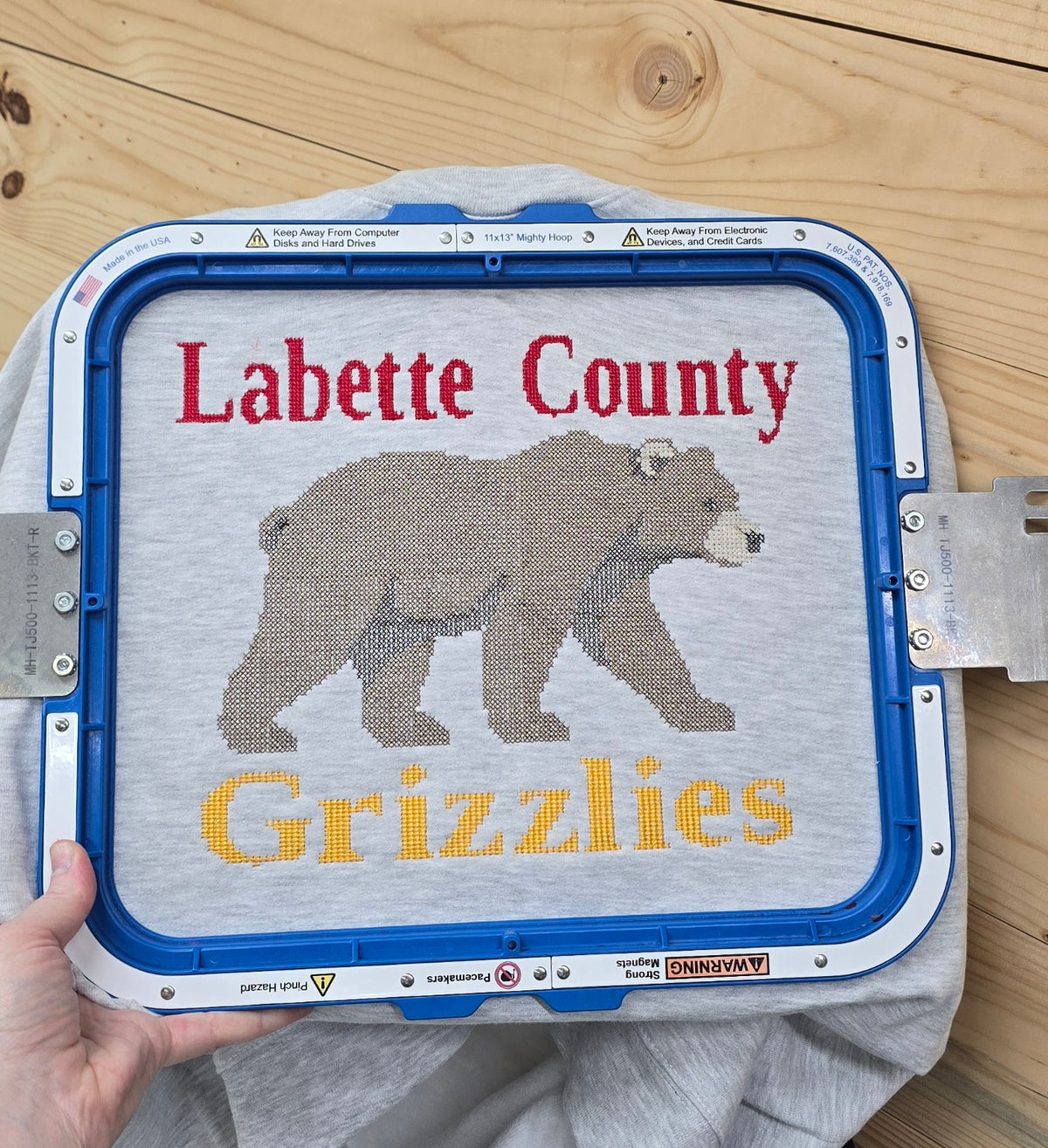 Close-up of Labette County Grizzlies bear embroidery on an ash grey sweatshirt