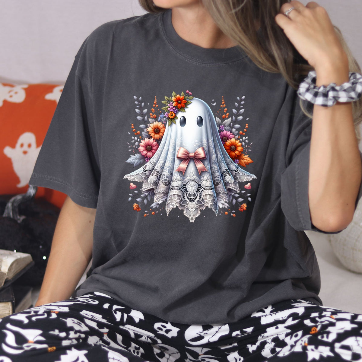 Woman wearing a Pepper Comfort Colors lace ghost Halloween shirt with a pink bow and fall florals