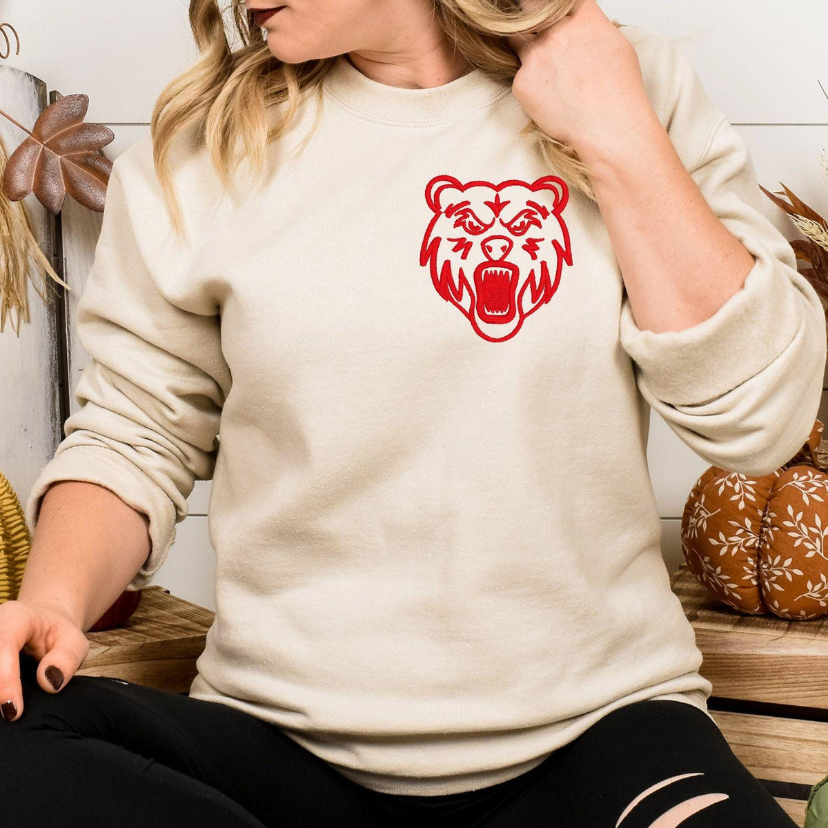 Sand sweatshirt with red left-chest bear mascot embroidery folded flat