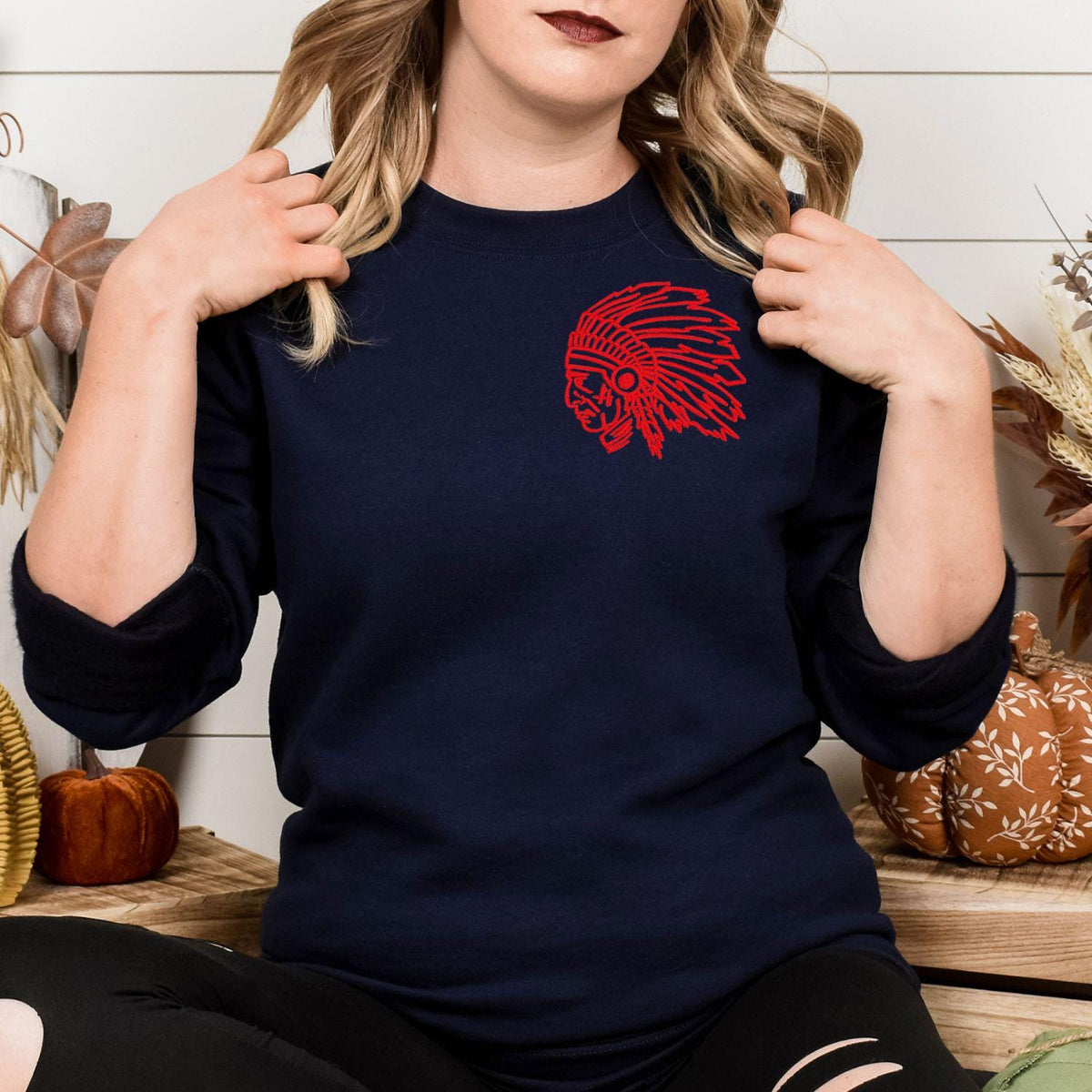 Navy sweatshirt with red left-chest headdress mascot embroidery modeled indoors