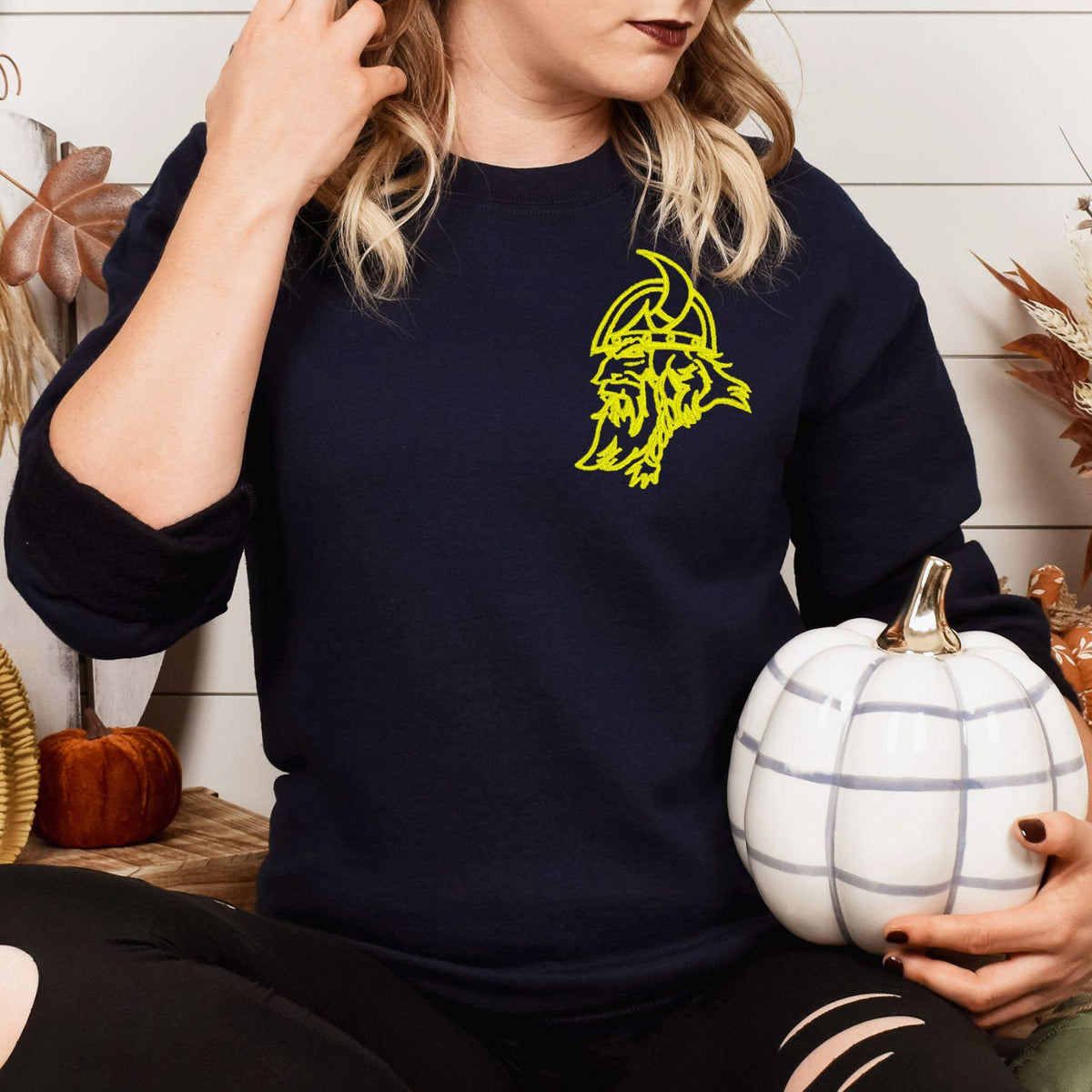 Navy left-chest Viking mascot sweatshirt modeled while holding a white pumpkin
