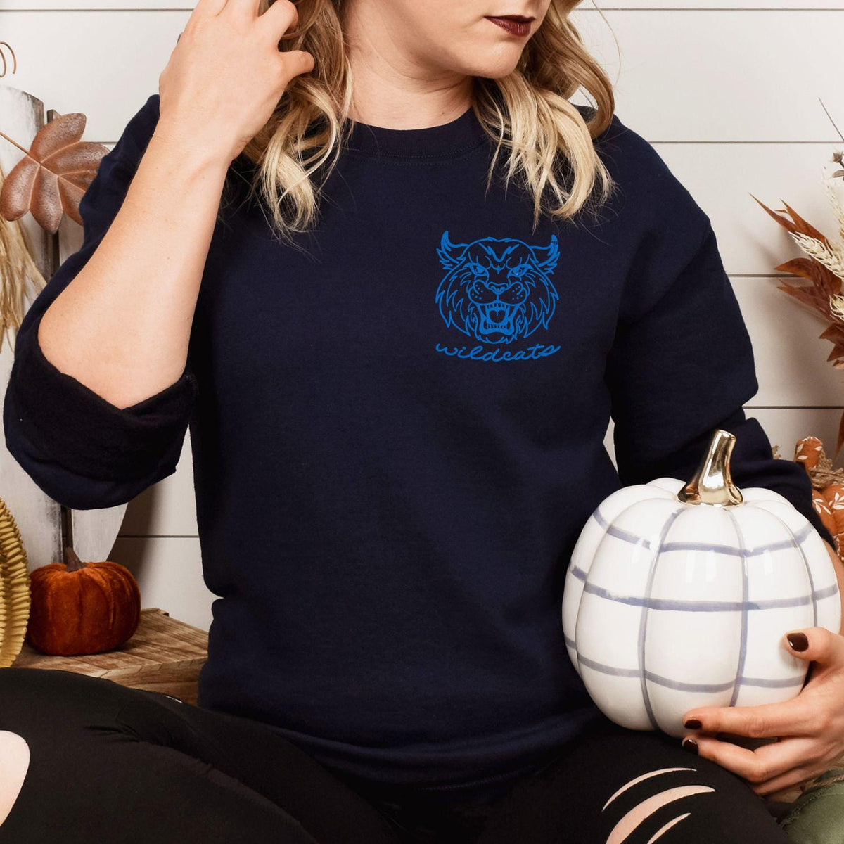 Navy Wildcats mascot sweatshirt modeled while holding a white pumpkin