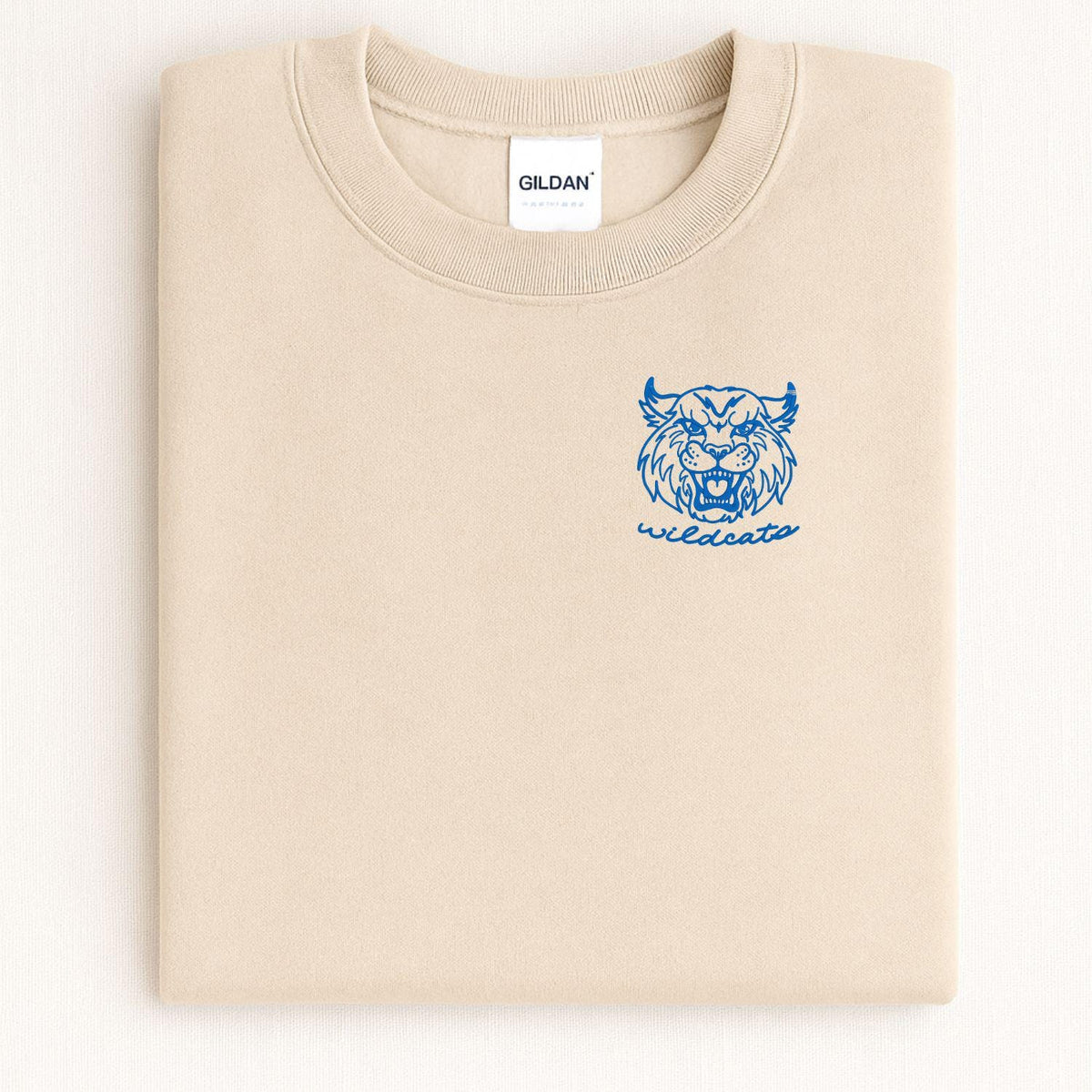 Sand Wildcats mascot embroidered crewneck folded on a light background
