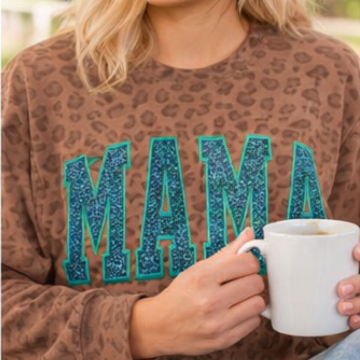 Close-up of teal glitter vinyl MAMA lettering on leopard sweatshirt