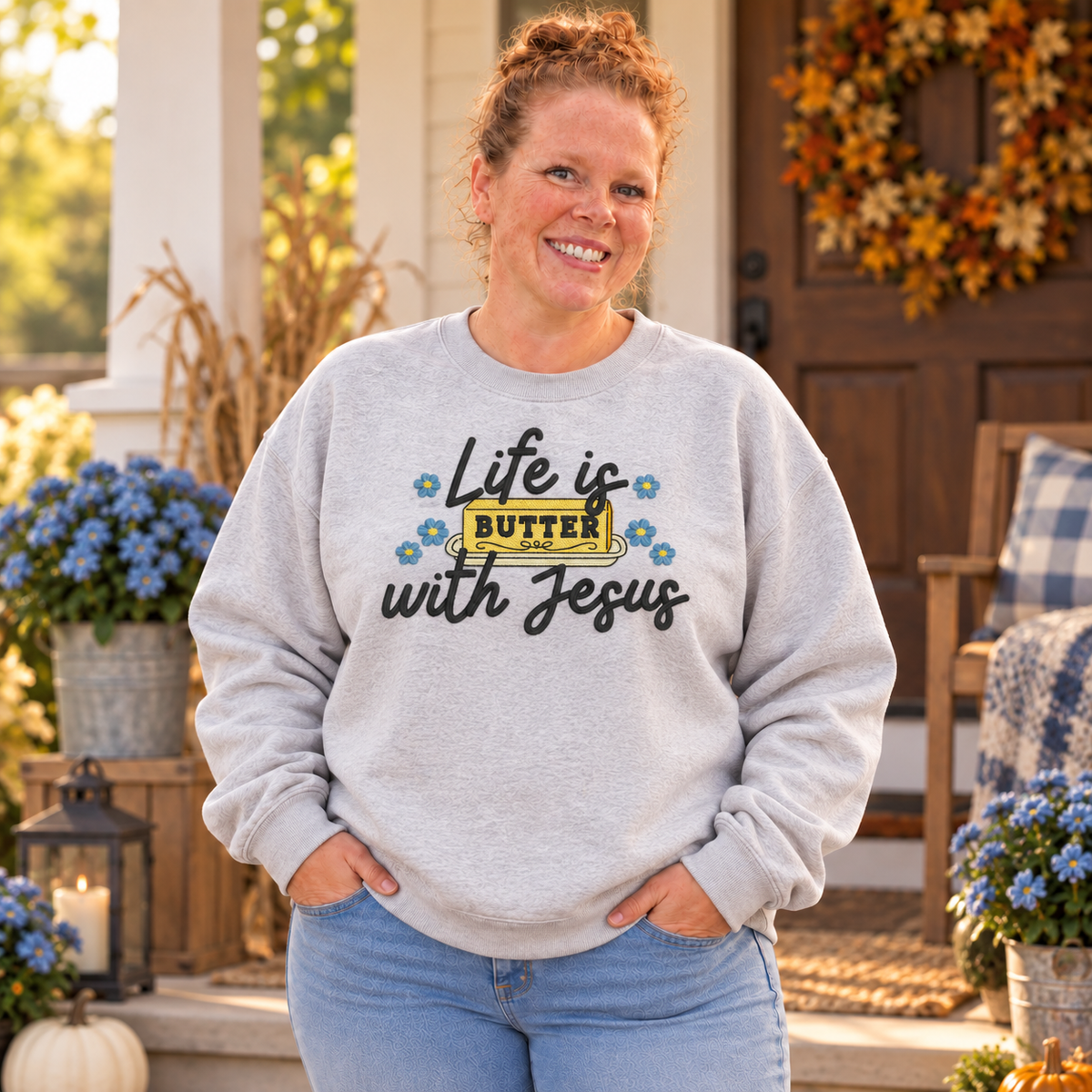 Woman wearing an Ash Life Is Butter With Jesus embroidered crewneck on a farmhouse porch