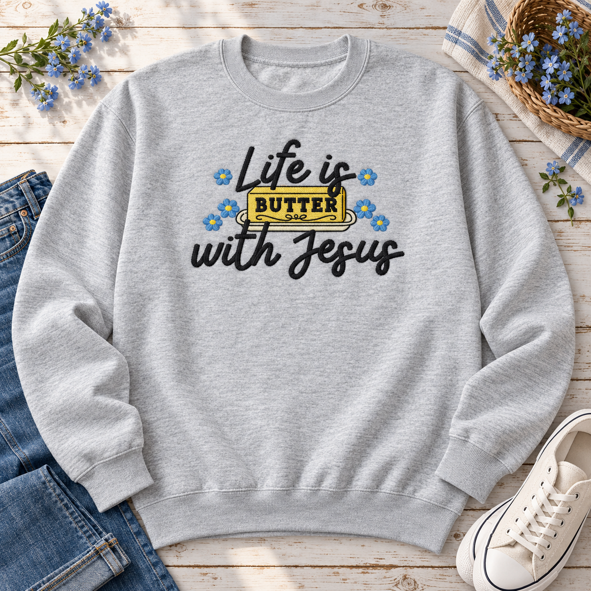 Ash embroidered Christian sweatshirt styled with jeans sneakers and blue flowers
