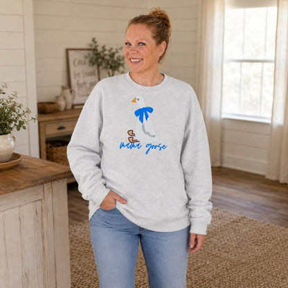 Woman wearing an ash gray Mama Goose crewneck featuring an embroidered white goose with a blue bow.