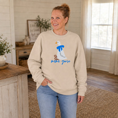 Woman modeling a sand-colored Mama Goose sweatshirt with an embroidered goose and bright blue bow.