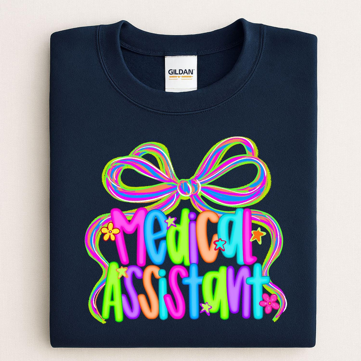 Navy sweatshirt with a colorful neon Medical Assistant bow graphic folded flat