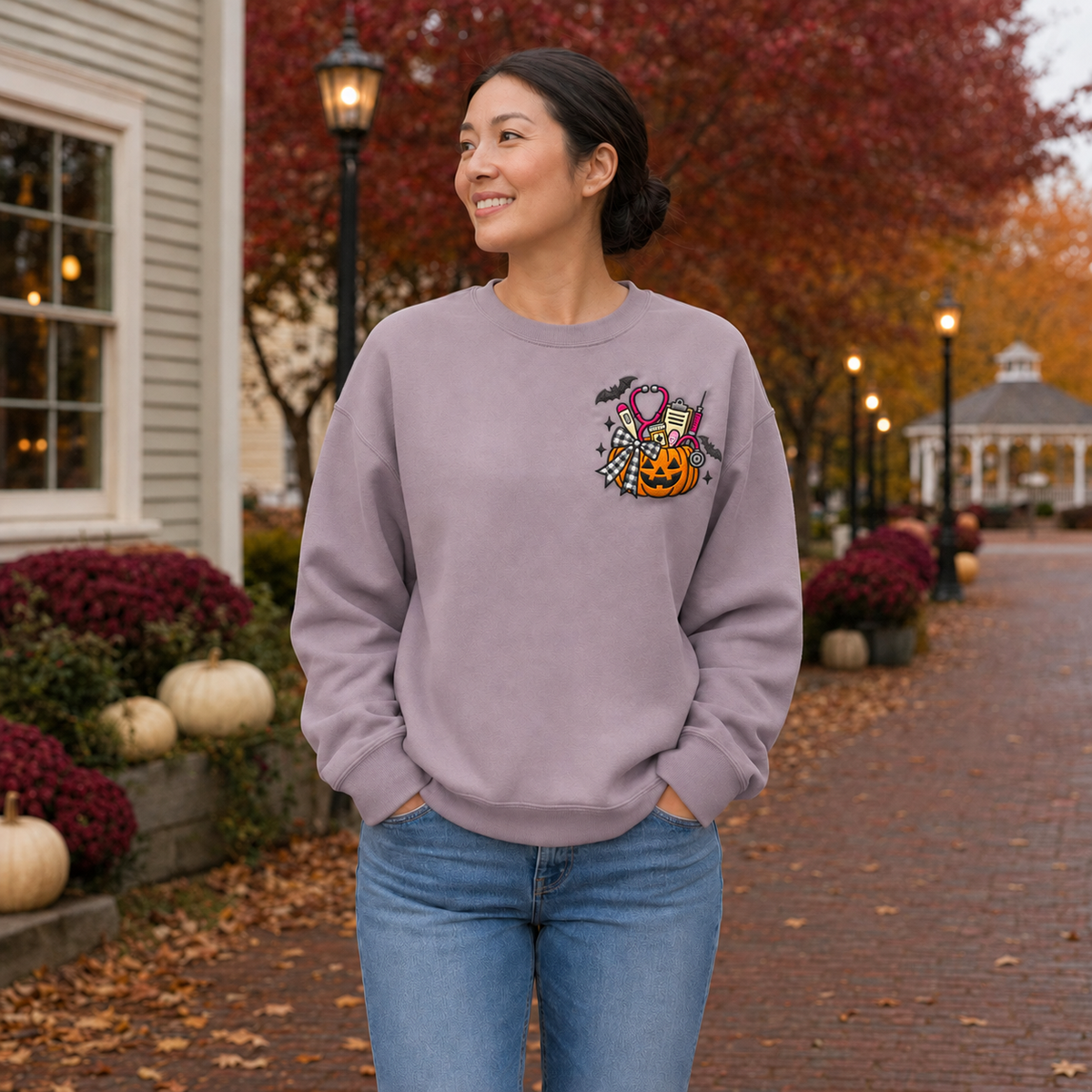 Adult woman wearing a Paragon sweatshirt with medical pumpkin embroidery on the left chest