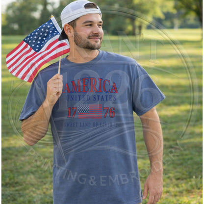 Man wearing blue patriotic America United States 1776 graphic tee holding American flag