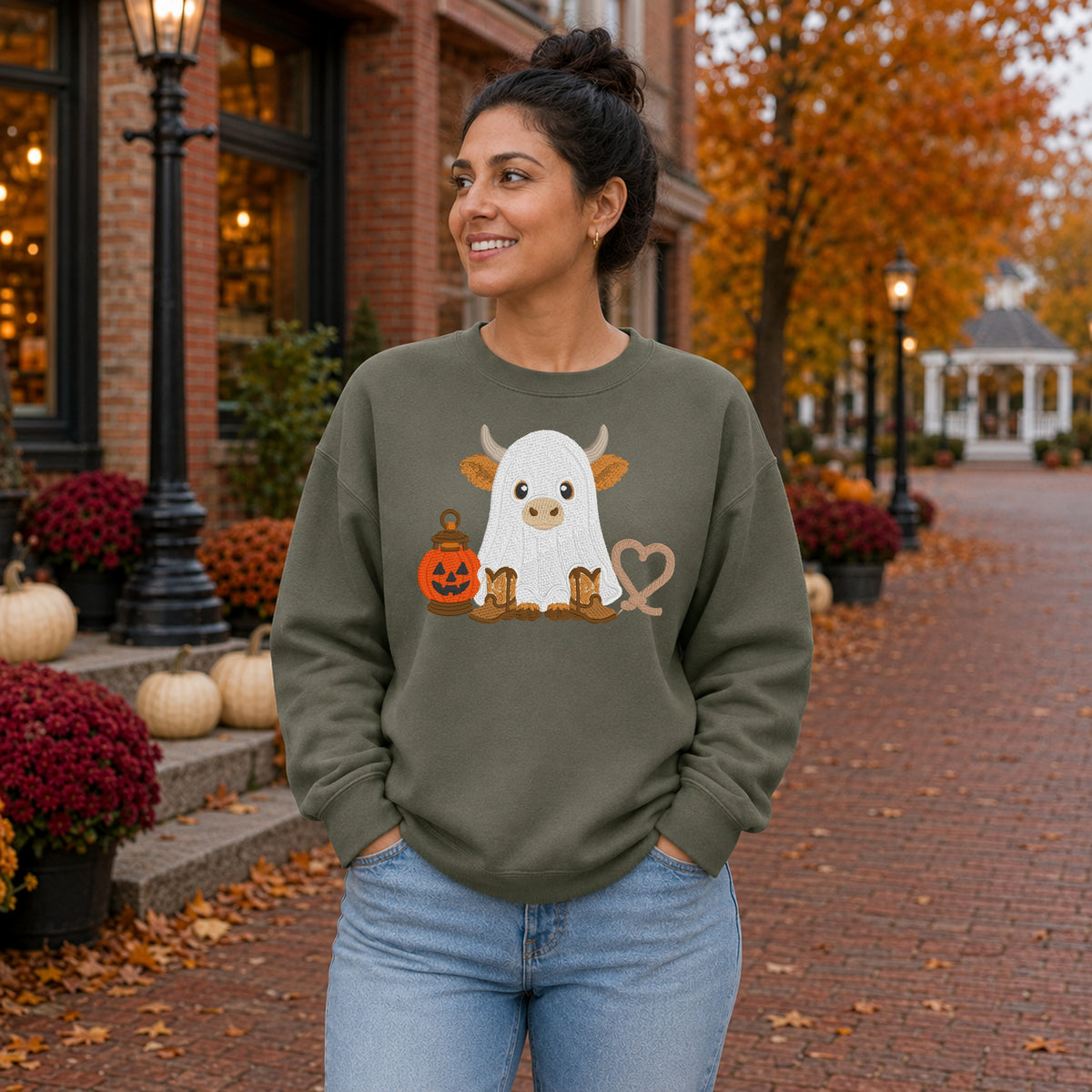 Woman wearing a Military Green ghost cow embroidered Halloween sweatshirt on a fall street