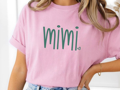 Person wearing a pink t-shirt with 'mimi' embroidered in green.