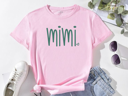 Pink t-shirt with 'mimi' text on a white surface with sunglasses and jeans.