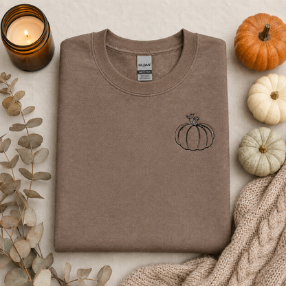 Brown Savanna Gildan Softstyle sweatshirt flat lay with small black pumpkin embroidery and cozy fall decor