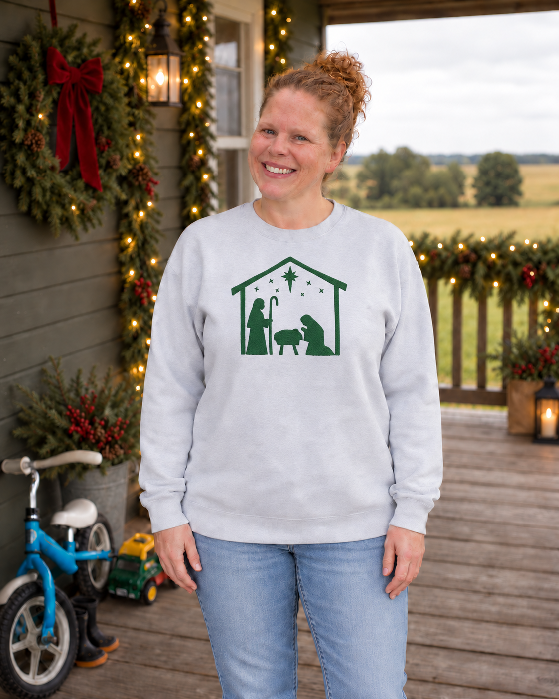 Samantha wearing an Ash Minimalist Nativity embroidered sweatshirt with evergreen custom thread on a Christmas porch