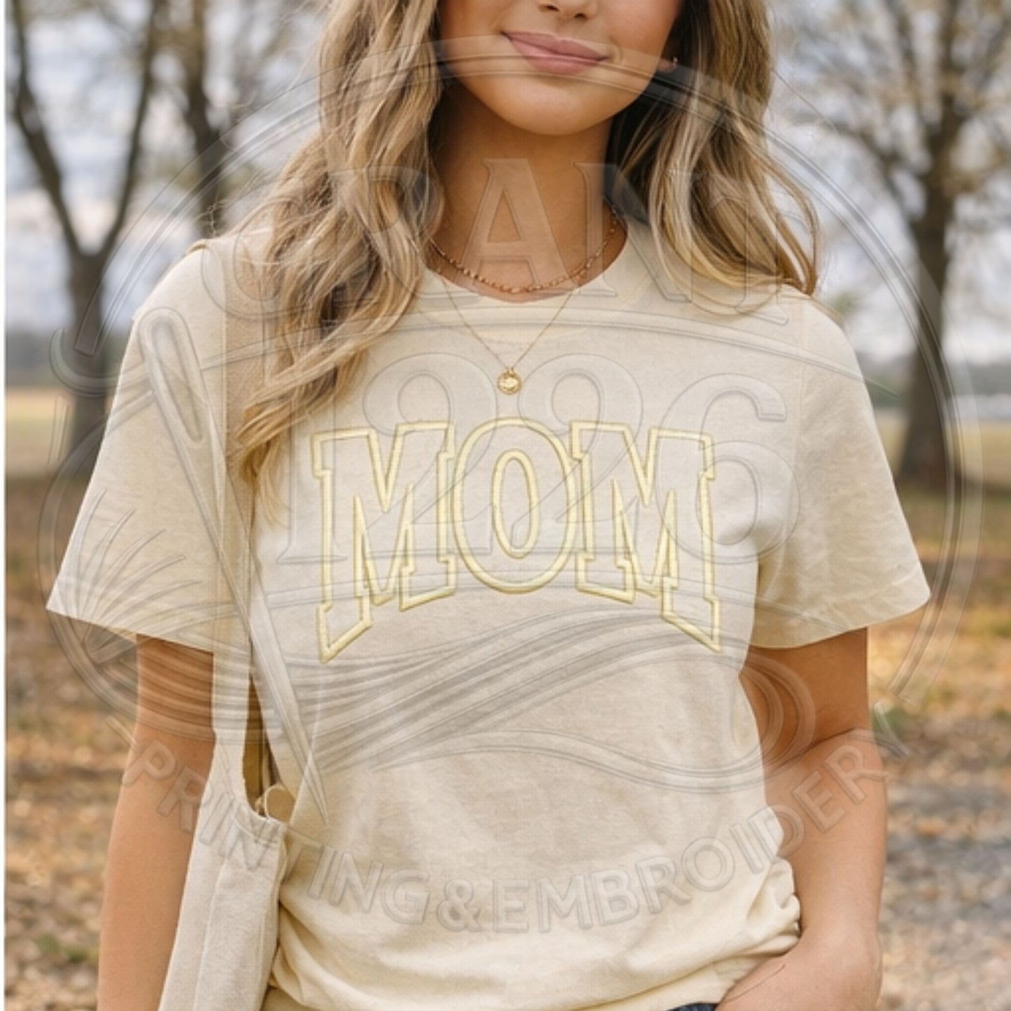 Woman wearing cream embroidered MOM Comfort Colors shirt outdoors
