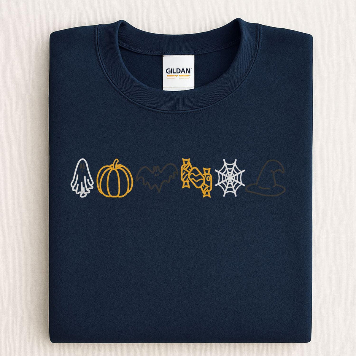 Folded Navy sweatshirt with embroidered ghost, pumpkin, bat, candy, web and witch hat