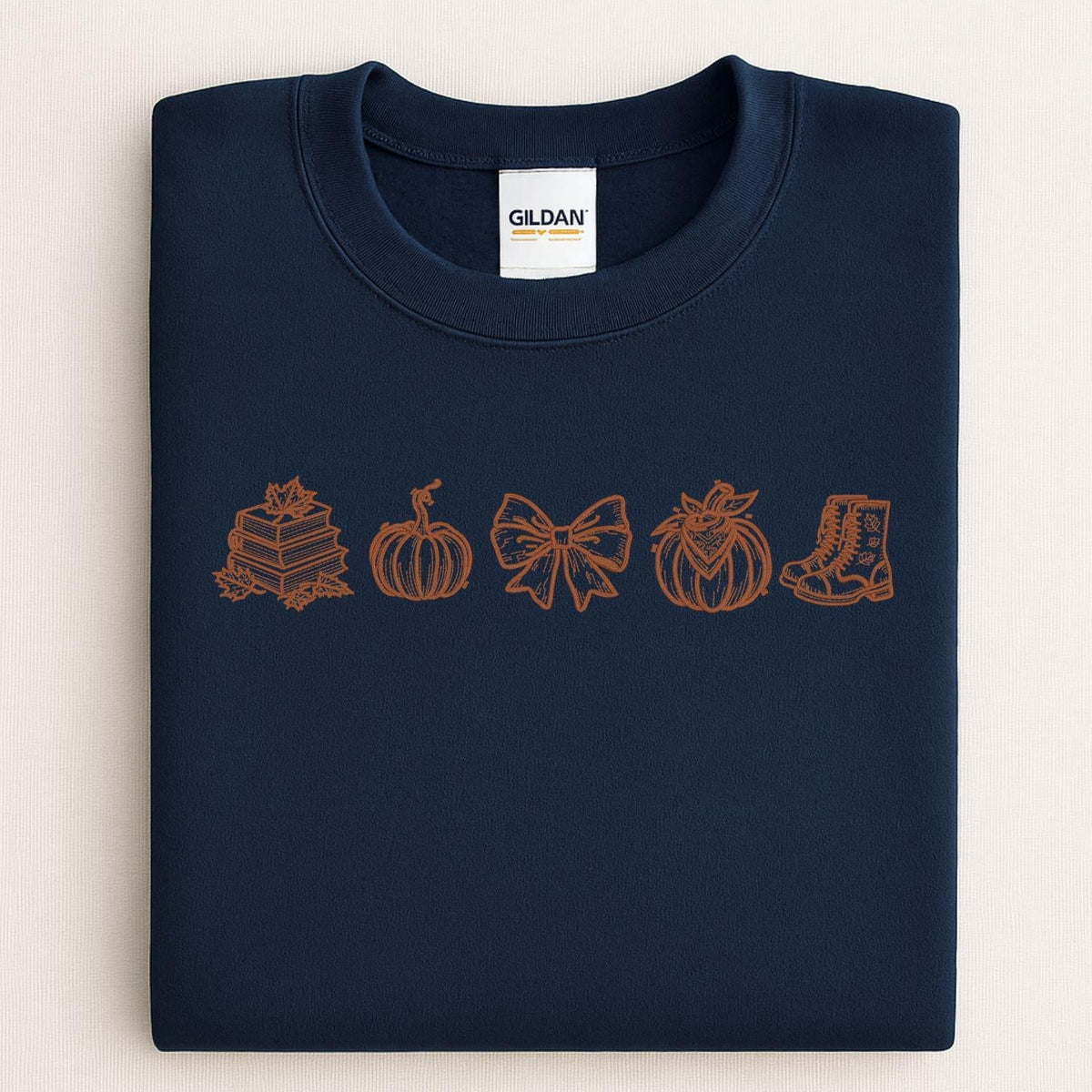 Navy Gildan sweatshirt with a brown embroidered row of fall books and pumpkins