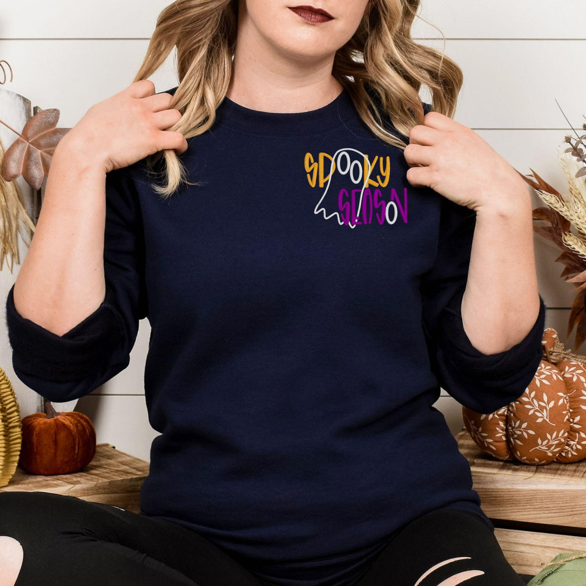 Navy spooky season ghost embroidery sweatshirt shown on a seated model