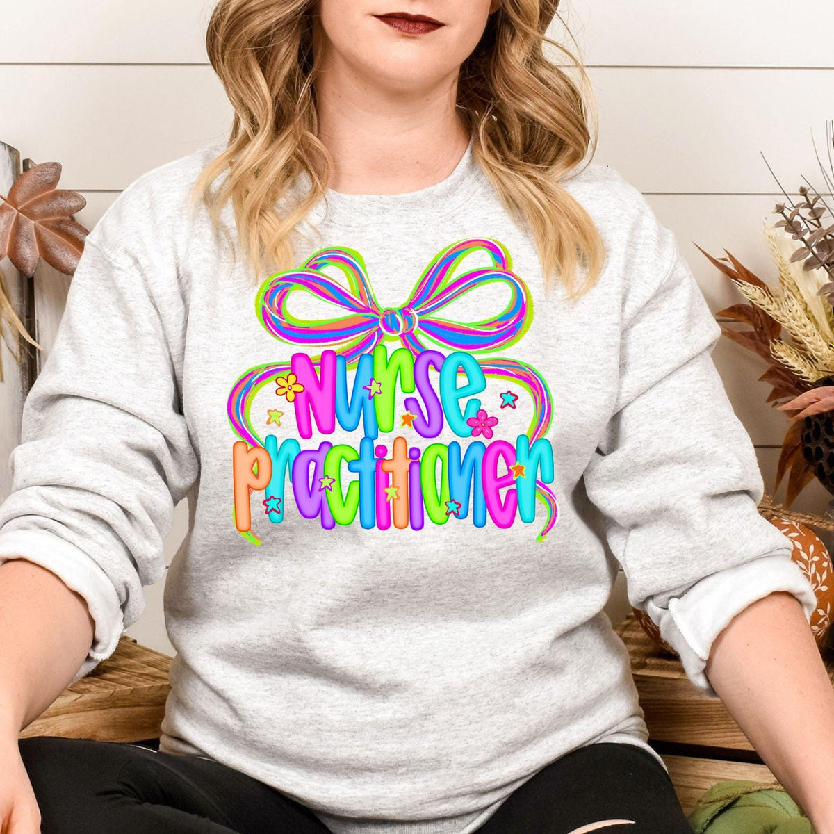 Model wearing ash gray Nurse Practitioner bow graphic sweatshirt