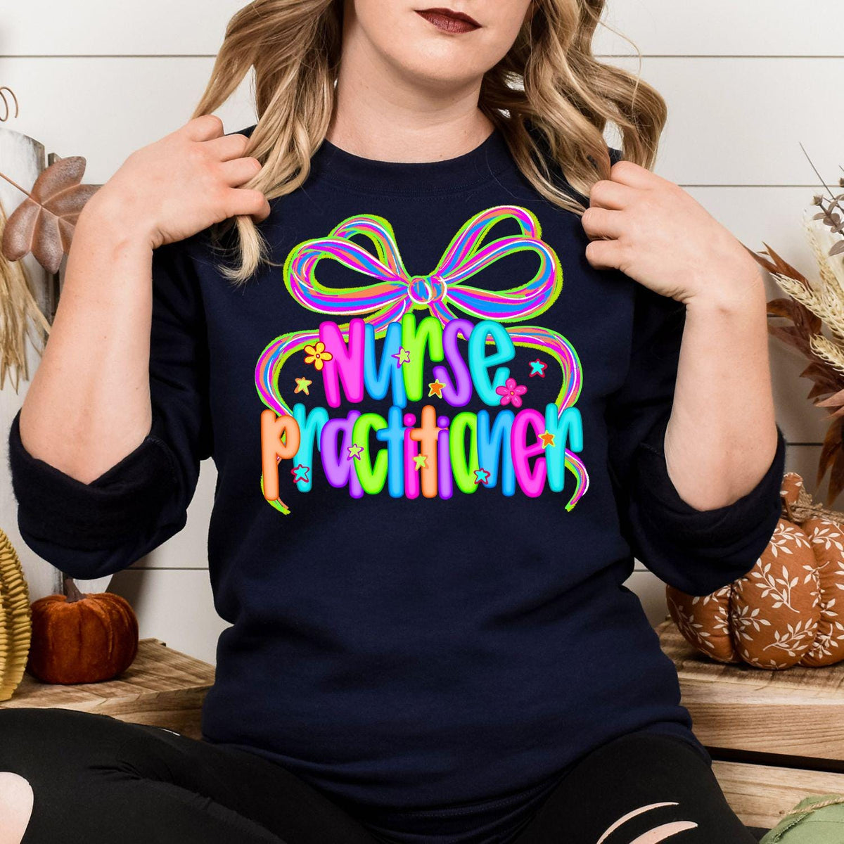 Front view of navy crewneck with colorful Nurse Practitioner bow graphic