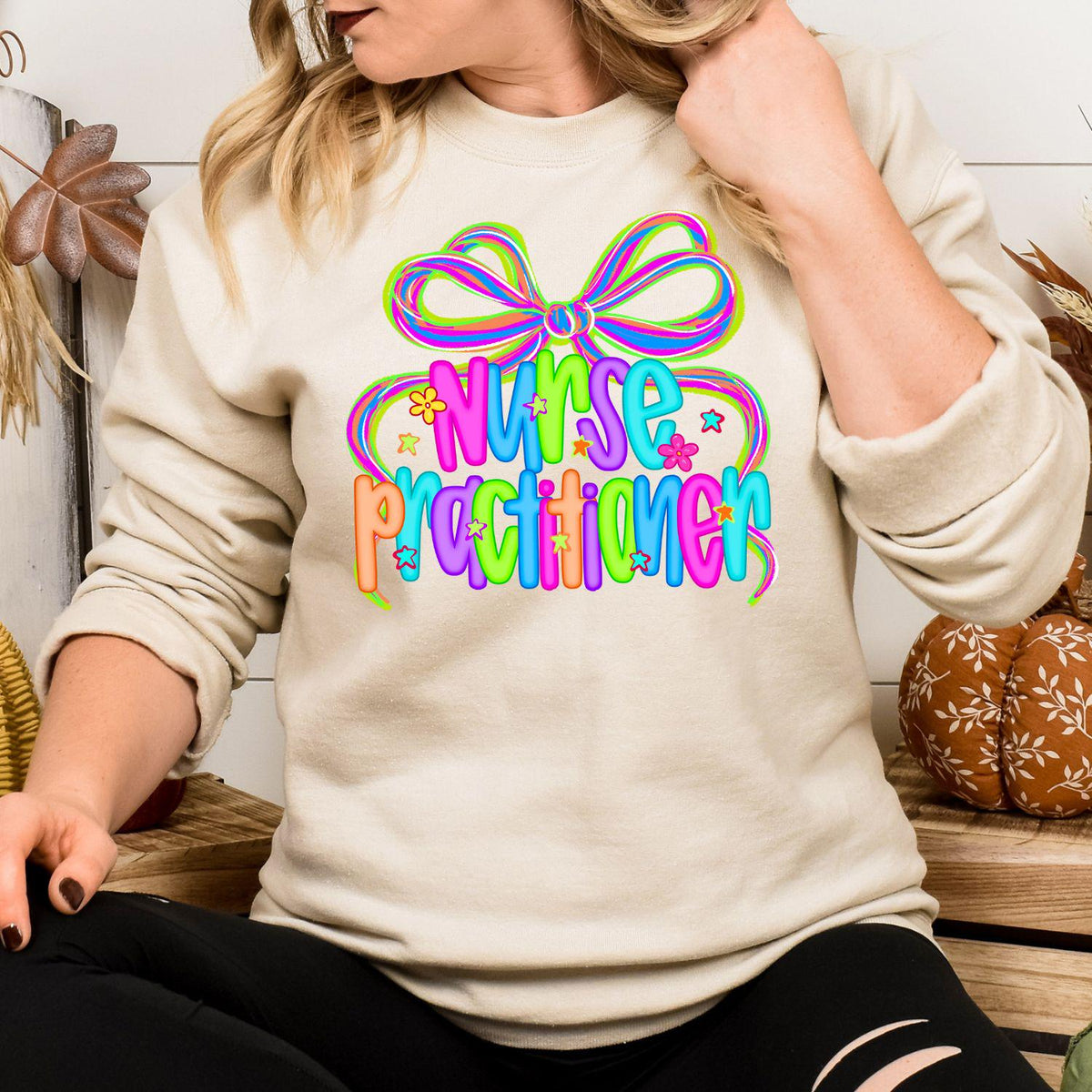 Model wearing sand sweatshirt with neon Nurse Practitioner bow graphic