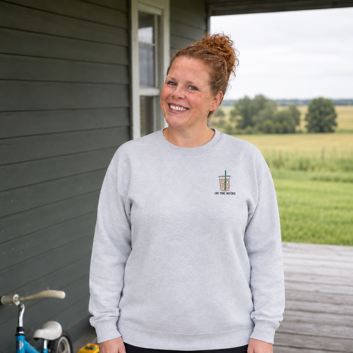 Samantha wearing an Ash Grey sweatshirt with small On the Rocks iced coffee embroidery