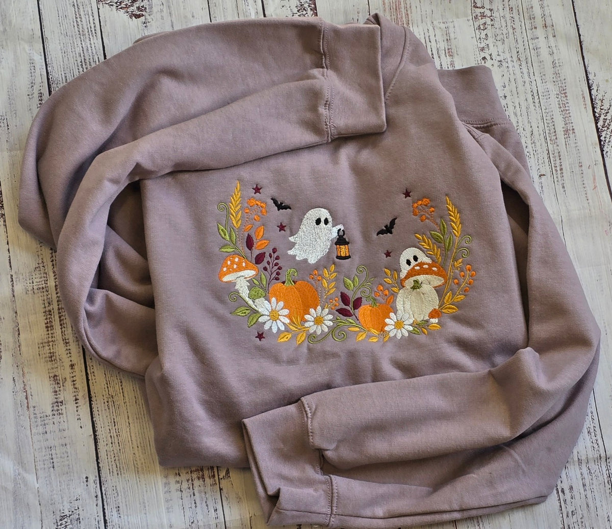 Close-up of floral ghost pumpkin and mushroom embroidery on Paragon Halloween sweatshirt