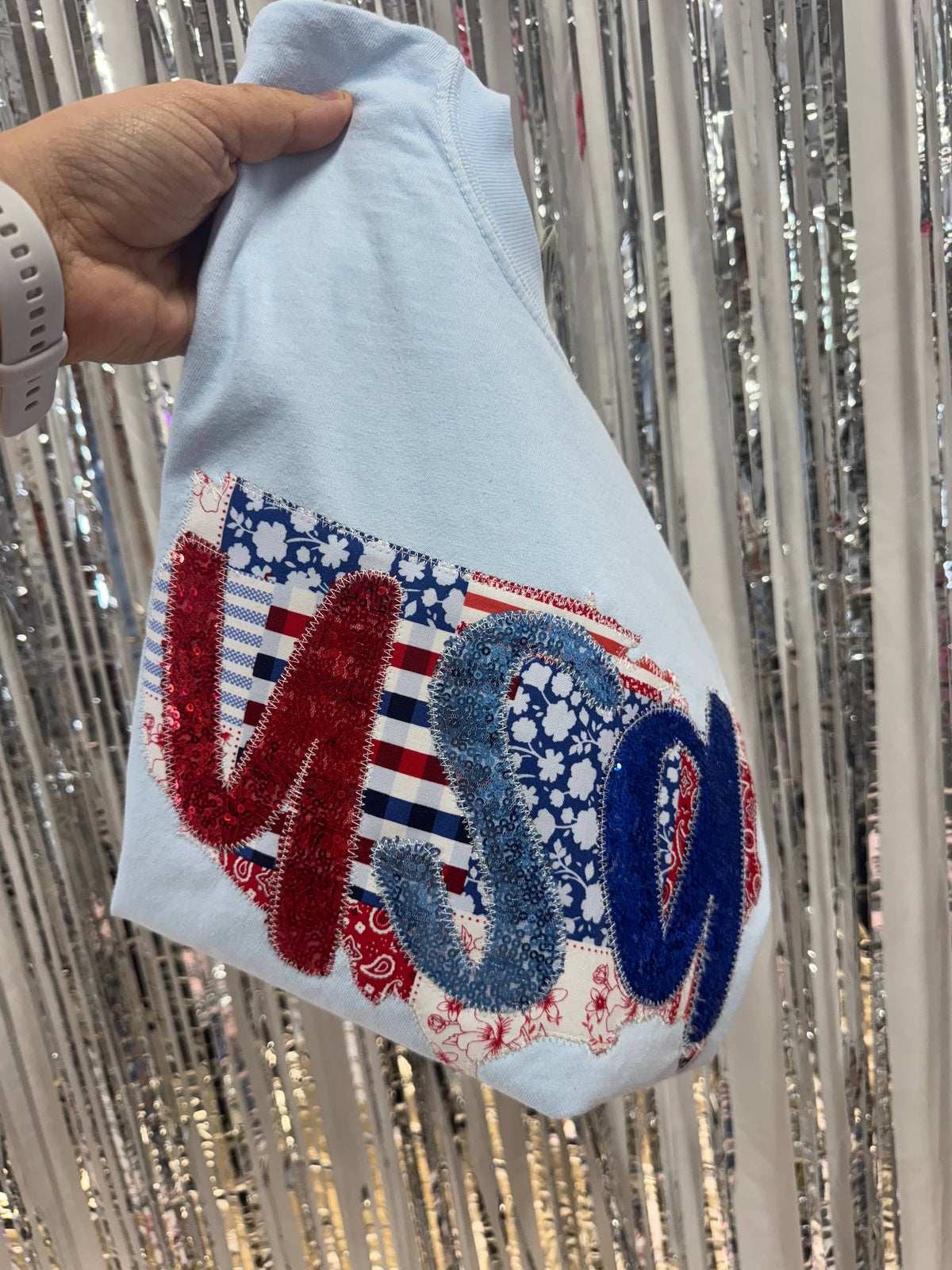 Light blue patchwork USA shirt held in front of a silver fringe backdrop