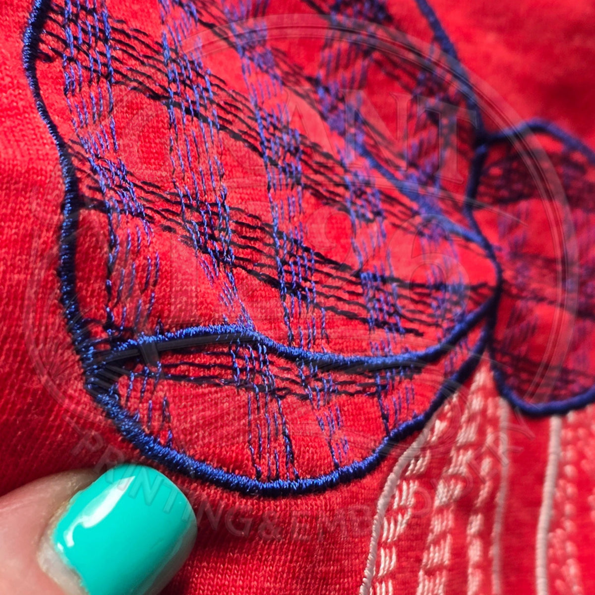Close-up of embroidered navy gingham bow detail on red kids shirt