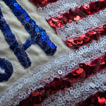Detailed embroidery view of patriotic sequin flag applique showing texture and craftsmanship.