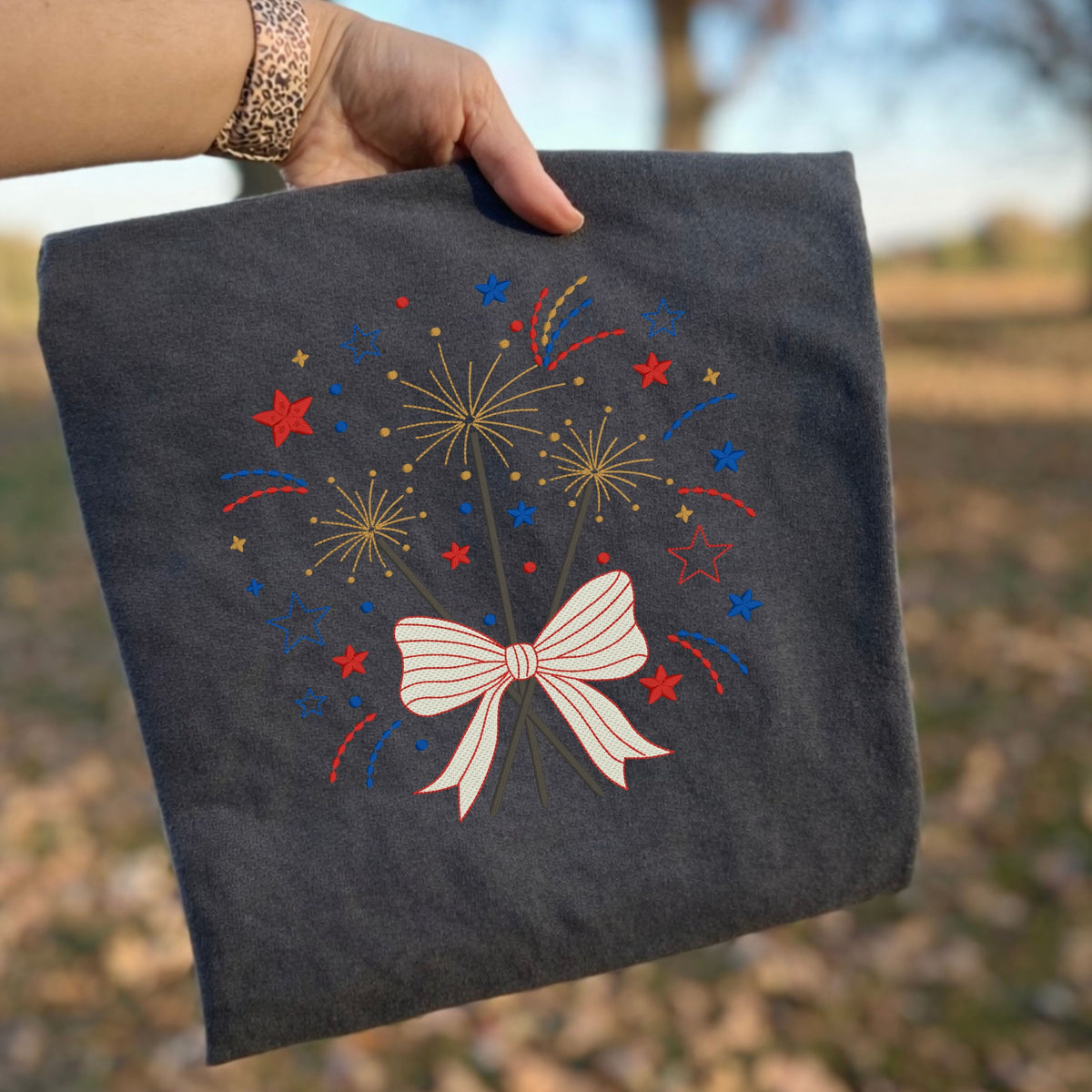 Pepper Comfort Colors T-shirt with embroidered patriotic fireworks and bow design