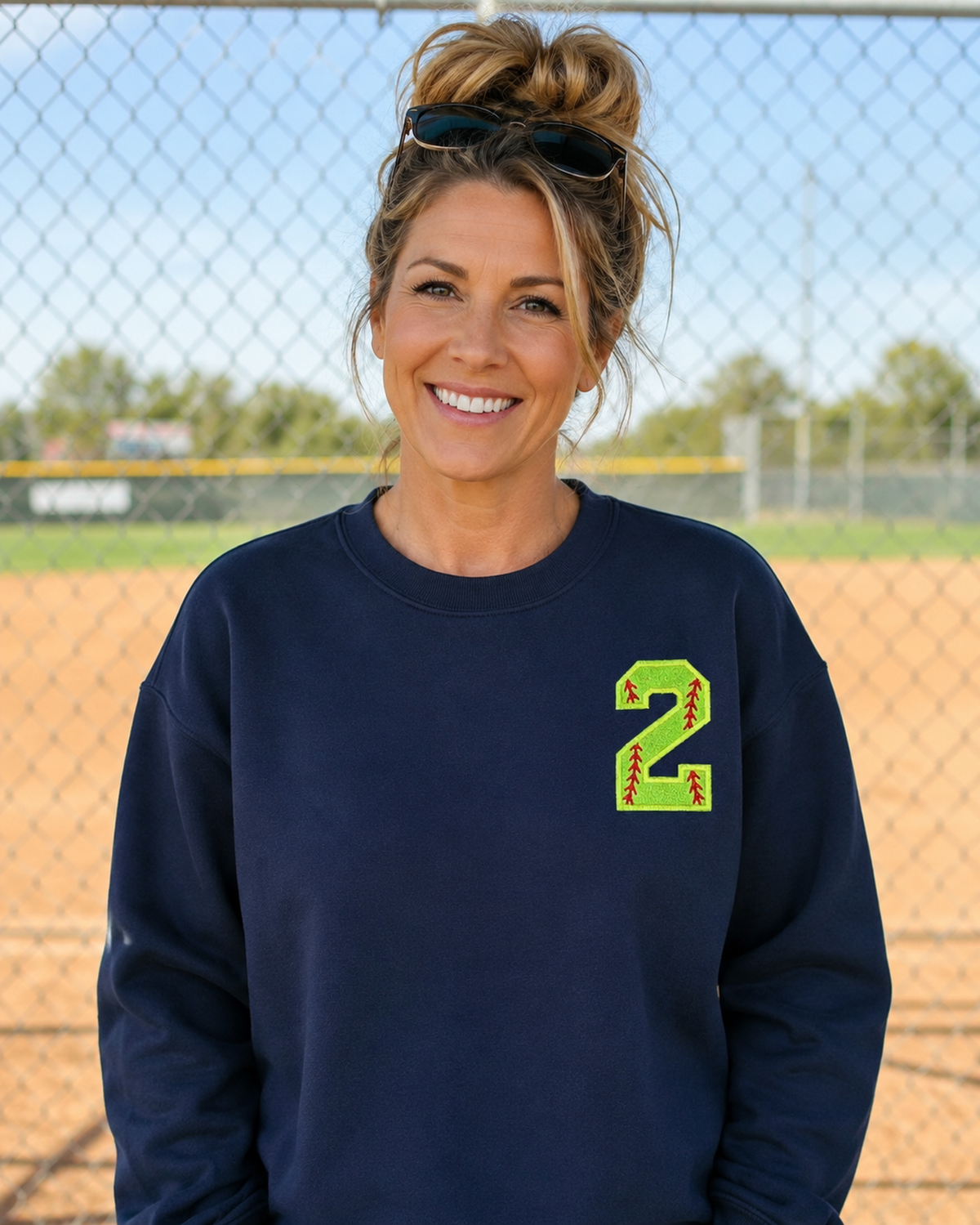 Navy personalized softball number 2 appliqué Gildan Heavy Blend sweatshirt at a softball field