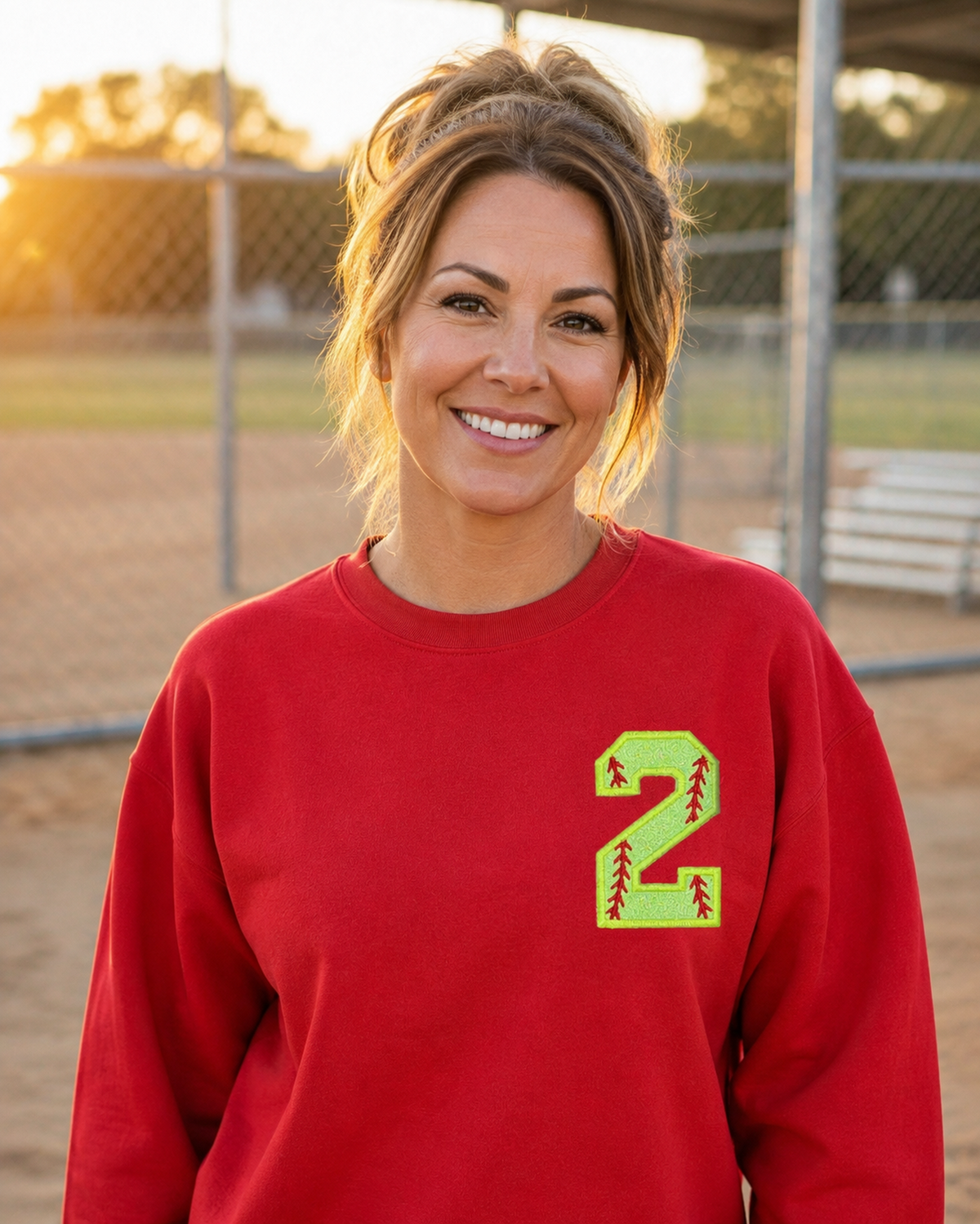 Red personalized softball number 2 appliqué Gildan Heavy Blend sweatshirt at a softball field