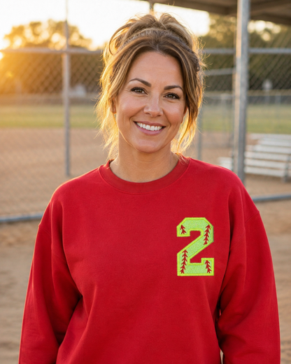 Red personalized softball number 2 appliqué Gildan Heavy Blend sweatshirt at a softball field