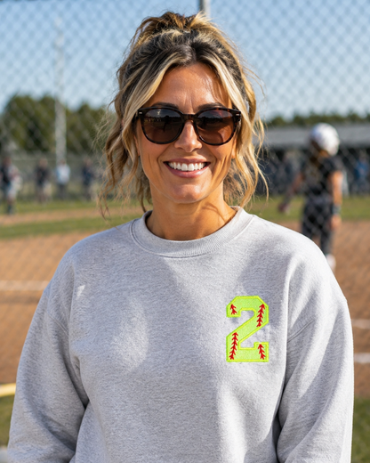 Sport Grey personalized softball number 2 appliqué Gildan Heavy Blend sweatshirt at a softball field