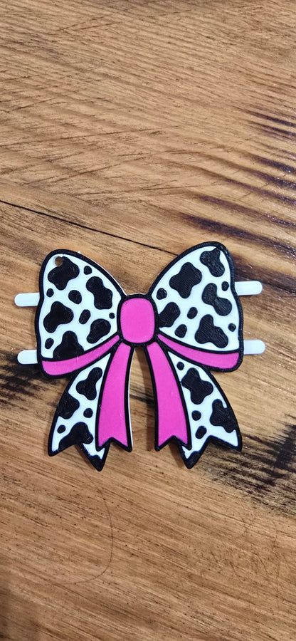 Pink, black, and white cow-print bow hair tie holder with side pegs
