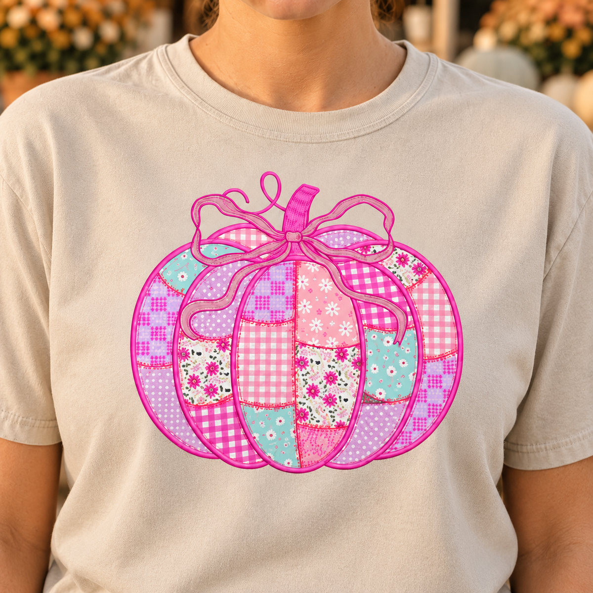 Close-up of the pink patchwork bow pumpkin DTG print on a Sandstone shirt