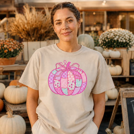 Woman wearing a Sandstone Comfort Colors shirt with a pink patchwork bow pumpkin DTG design at a fall market