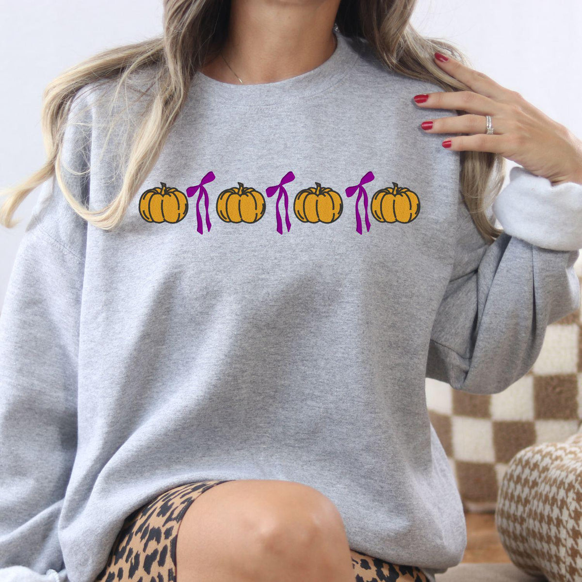 Ash Gildan 18000 sweatshirt with embroidered orange pumpkins and pink bows in a fall lifestyle setting