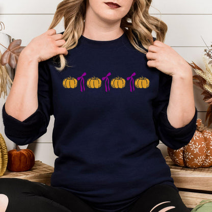 Navy Gildan 18000 sweatshirt with embroidered orange pumpkins and pink bows in a fall lifestyle setting
