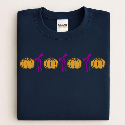 Folded Navy Gildan sweatshirt with a row of embroidered pumpkins and pink bows