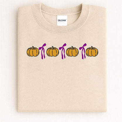 Folded Sand Gildan sweatshirt with orange pumpkin and pink bow embroidery