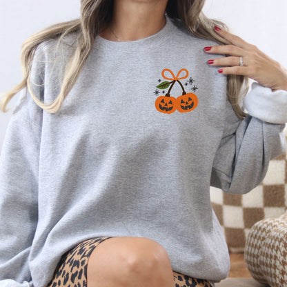 Ash Gildan sweatshirt with a small embroidered pair of Halloween pumpkins