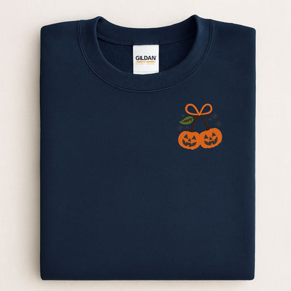 Folded Navy Gildan crewneck with two orange embroidered jack-o-lanterns