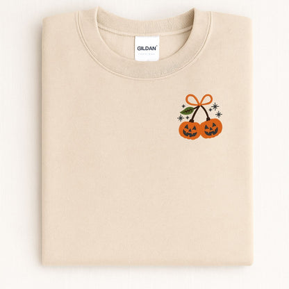 Folded Sand Gildan sweatshirt showing the embroidered pumpkin pair design